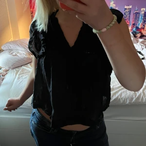Svart croppad blus med v-ringning - Supersnygg festtopp, ganska croppad med korta ärmar. Tyget är lite see-through, men inte så mycket. 