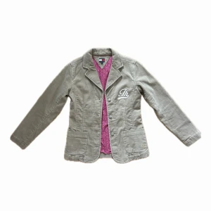 Beige jacka från Tommy Hilfiger - Snygg beige jacka från Tommy Hilfiger med vit broderad logga på bröstet. I perfekt skick, bara använd några få gånger då den tyvärr är för liten. Står M i storlek, men skulle säga den passar bättre som xs/s💕