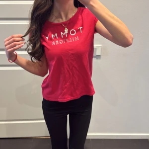 Rosa t-shirt från Tommy Hilfiger - Säljer en rosa t-shirt från Tommy Hilfiger med silverfärgad logga framtill. T-shirten är i ekologisk bomull, har rund halsringning och korta ärmar. Perfekt för en avslappnad och stilren look. Köpt i NK och är äkta. Finns ej i butik längre och säljer den pga att jag inte har användning av den. Det är i barn storlek men passar på xs och ner. Använt ett par gånger men är nästan helt nytt skick.💗(original pris 500kr) 