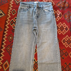 Ljusblå raka jeans från H&M - Säljer ett par ljusblå jeans från H&M med klassisk femficksdesign och raka ben. Jeansen har normal passform och hög midja, perfekta till vardags. Tidlös modell som är enkel att matcha med olika toppar.