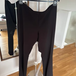 Svarta kostymbyxor från Zara - Snygga svarta kostymbyxor från Zara med klassisk passform. Byxorna har hög midja och raka ben, perfekta till en stilren look. Tillverkade i ett mjukt och följsamt material som känns bekvämt hela dagen.