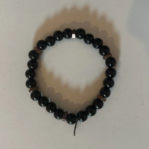 Svart pärlarmband - Snyggt armband med svarta glansiga pärlor och några silvriga detaljer. Elastiskt band gör det enkelt att ta på och av. Perfekt accessoar för att lyfta din stil.