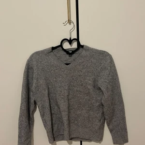 Grå v-ringad tröja från Uniqlo - Säljer en klassisk grå v-ringad tröja från Uniqlo. Tröjan har lång ärm och är tillverkad i ett mjukt material som passar perfekt till lager-på-lager. Enkel och stilren design som funkar året runt.