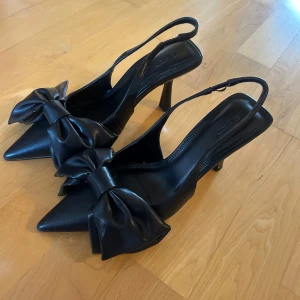 Klacksko med rosett - Säljer dessa så fina svarta klackar från NA-KD då de var för stora för mig. Helt oanvända men de har en mindre defekt som syns på sista bilden men det är inget som man tänker på när man har på sig skon. Nypris 599kr