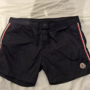 Svarta badshorts från Moncler  - Svarta badshorts från Moncler  som är fetta Fick dem som en present av mina farsa. De passar från L-XL till då XXL som är storleken på dem. Shortsen har snörning i midjan och bakficka med knapp. Perfekta för stranden eller poolen. Garanterat att få guzzar me dem här i sommar.