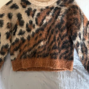 Leopardmönstrad fluffig tröja från & Other Stories - Supermjuk och fluffig tröja från & Other Stories Paris Atelier i leopardmönster. Tröjan har rund halsringning, långa ärmar och är i beige, bruna och svarta toner. Perfekt statement-plagg för dig som gillar djurmönster! Köpt för 1500