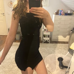 Svart tight kortklänning från H&M - Säljer en svart tight kortklänning med fyrkantig ringning och tight design. Klänningen har en enkel och stilren look som framhäver figuren. Klänningen är inte fläckig det är spegeln!! Lapp borttagen men är från H&M och är i storlek XXS. Säljer eftersom den aldrig kommer till användning.