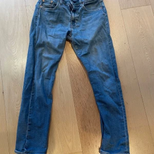 Blå Levis 502 jeans - Klassiska blå Levis 502 jeans med raka ben och fem fickor. Byxorna har knappgylf och är tillverkade i slitstarkt denim. Perfekta för en avslappnad stil och passar till det mesta. Ikonisk Levis-lapp bak i midjan.