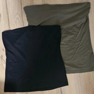 Två tubtoppar i svart och olivgrön - Säljer två enkla och stilrena tubtoppar, en i svart och en i olivgrön färg. Perfekta att matcha med jeans eller kjol för en avslappnad look. Mjukt material som sitter skönt mot kroppen.