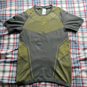 Gymshark Onyx V4 - Säljer en T-shirt från Gymsharks Onyx kollektion i storlek medium fast i deras fjärde upplaga i färgen grå och gul. T-shirten är fortfarande i jättebra skick, skulle säga 8.5/10 (bedöm själv från bilderna). Riktigt sällsynt i denna condition!