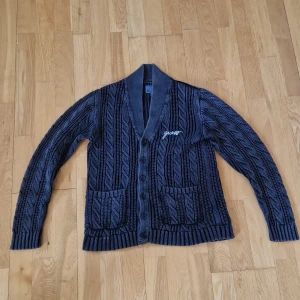 Mörkgrå stickad kofta från Guess - 🔥 GUESS stickad tröja – svart & clean 🔥 Säljer en riktigt snygg och mjuk stickad tröja från GUESS 🖤 – perfekt till hösten 🍁 och vintern ❄️. Det är en klassisk modell med diskret logga framtill och clean look som funkar både till vardags och om du vill klä upp dig lite mer ✨ Tröjan är i superfint skick, inga noppor eller fläckar. Den sitter skönt och passar dig som är runt 160–168 cm lång 📏 Mjuk, lite rakare passform och riktigt bekväm 🙌 Jag fraktar snabbt och säkert med Postnord eller Instabox 📦💨