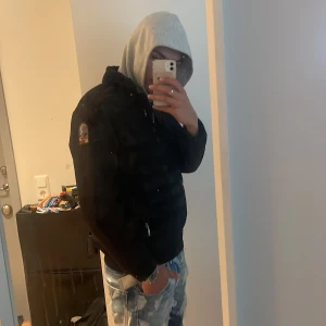 Svart pufferjacka från Parajumpers - Säljer en svart pufferjacka från Parajumpers med klassisk patch på ärmen. Jackan har quiltad framsida, dragkedjor på fickor och bröst, samt ribbade muddar. Perfekt för höst och vinter, riktigt snygg och stilren modell.