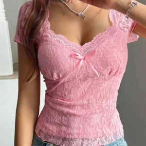 Rosa spetstopp med rosett - Helt ny!!!! Gör liten tyvärr. Köpte för 150. Söt rosa topp i spets med korta ärmar och v-ringning. Toppen har en liten rosett framtill och är figurnära i modellen. Perfekt för dig som gillar romantisk stil och detaljer.