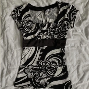 Svartvit blommig topp med markerad midja - Inte mina bilder! Säljer en svartvit topp från Only med stora blommiga mönster och markerad midja. Toppen har korta ärmar, rundad urringning och är figurnära. Perfekt för dig som gillar grafiska mönster och vill sticka ut. Ingen storlekslapp, köpt här på Plick. Säljaren sa att den var i strl S! 