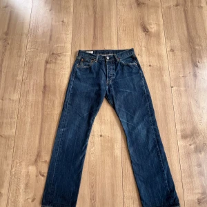 Levi's 501 mörkblå jeans W30 L30 - Klassiska Levi's 501 jeans i mörkblå denim med raka ben och normal passform. Byxorna har fem fickor, knappgylf och ikonisk läderpatch bak i midjan. Perfekta för en avslappnad och tidlös stil. Bra skick med en snygg urtvättad design på jeansen bara att höra av dig om du har fler frågor! Mvh Theo