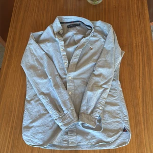 Ljusblå skjorta från Ralph Lauren - Tjena säljer denna Klassiska  ljusblå skjorta från Ralph Lauren i bomull med broderad logga på bröstet. Skjortan har lång ärm, knappar framtill och klassisk krage. Perfekt för en stilren och avslappnad look.