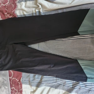 Svarta leggings med gröna detaljer - Snygga svarta leggings med coola gröna paneler vid bensluten. Stretchigt material som sitter tight och är perfekt för träning eller chill. Enkel design utan synliga loggor eller fickor.