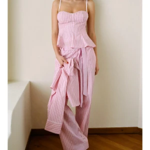 Rosa randigt set med byxor och topp - Säljer ett par rosa byxor med tunna vertikala ränder och ett brett knytband i midjan samt en matchande topp. As najs set!! Men säljer pga då det var för stora på mig❤️