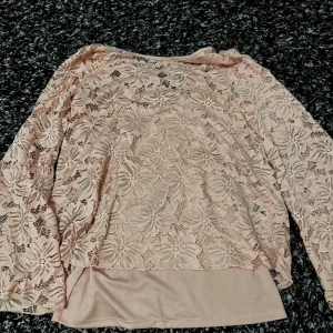 Ljusrosa spetsblus med blommönster - Säljer en ljusrosa blus med vackert blommigt spetsmönster och långa ärmar. Blusen har ett innerfoder och dekorativa band i ryggen. Perfekt för dig som gillar romantisk stil! Passar jätte bra med vita jeans och ballerina skor. Lite lite ljusare irl