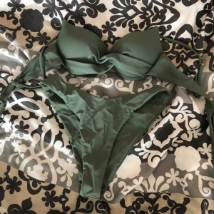 Olivgrön bikini med twistad topp - Snygg olivgrön bikini med twistad detalj på toppen och klassiska bikinitrosor. Överdelen har vadderade kupor och knytband i ryggen. Perfekt för stranden eller poolen. Från shein men är oanvänd så vilken innebär ingen prislapp men aldrig använt. 