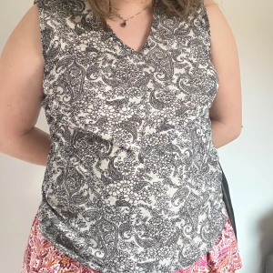 Svartvit blommig ärmlös topp från KappAhl Vintage  - Säljer en snygg ärmlös topp från KappAhl i svartvitt med detaljerat blommigt och paisleymönster. Toppen har v-ringning och är tillverkad i mjuk bomull, perfekt för varma dagar.