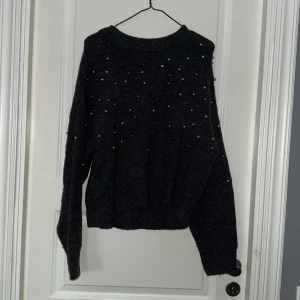 Stickad tröja med pärlor - En mörk grå/svart stickad tröja med pärlor. Tröjan är från H&M och är i storlek S. Materialet på tröjan är väldigt mjukt