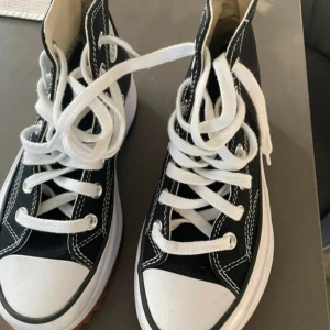 Svarta Converse Chuck Taylor All Star sneakers - Säljer ett par klassiska svarta Converse Chuck Taylor All Star sneakers med vit tå och vita snören. Skorna har hög modell, tydliga vita sömmar och en tjock, räfflad sula som ger extra attityd. Perfekta för dig som gillar streetstyle och tidlös design.