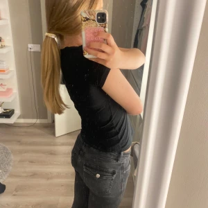 Svarta jeans med knappar på fickorna - ett par svarta jeans från lager 157 med fina knappar bak på fickorna som en detalj.