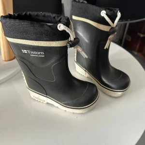 Svarta gummistövlar från Tretorn - Svarta fodrade gummistövlar från Tretorn med vit sula och beige detalj 