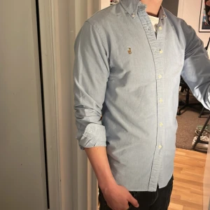 Ralph Lauren Skjorta - Tja säljer en Ralph lauren skjorta i färgen ljusblå och i storlek M. Nypris 1595 KR mitt pris 299 KR. Inga defekter som hål eller fläckar. Skriv vid frågor eller funderingar.