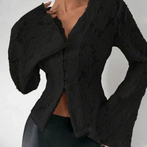 Svart croppad blus med vida ärmar - Trendig svart blus och vida, långa ärmar. Blusen har knappar framtill och spets  tyg som ger en cool look. Perfekt för dig som vill sticka ut med en unik topp.