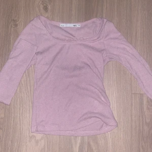 Ljusrosa ribbad topp med spetsdetalj - Säljer en ljusrosa ribbad långärmad topp från 157 med trekvartsärm och fin spetsdetalj vid ringningen. Toppen har en feminin och enkel design som passar perfekt till många olika outfits. Använd runt 3 gånger o säljer då den är för liten. Sitter väldigt tajt, som en xxs. 