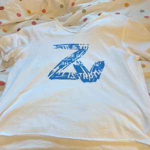 Vit t-shirt Zadig & Voltaire blå print - Vit t-shirt från Zadig & Voltaire med blått grafiskt Z-tryck framtill. Rund halsringning med två små knappar och diskret broderad ZV-logga på ärmen.  Säljer den då jag ej andvänder den men har andvänt en gång. Är i väldigt bra skick.