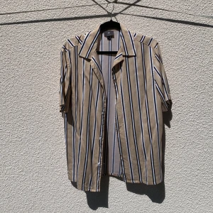 Beige och vit randig skjorta från H&M - Säljer en beige skjorta med svarta och vita ränder från H&M. Skjortan har korta ärmar, klassisk krage och knäppning framtill. Tillverkad i 100% viskos, i storlek S.