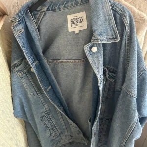 Oversized jeansjacka från Zara - Säljer en klassisk ljusblå jeansjacka från Zara med oversized passform. Jackan har knappar framtill, två bröstfickor och klassisk krage. Perfekt att slänga över en hoodie eller t-shirt för en avslappnad look.