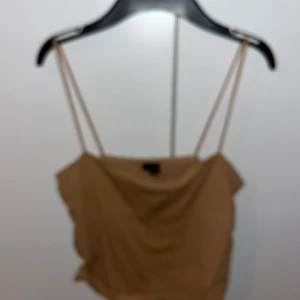 Beige linnetopp från Gina Tricot - Snygg beige linnetopp från Gina Tricot med smala axelband. Perfekt för varma dagar eller som ett lager under en jacka. Enkel och stilren design som passar till det mesta. Skriv för fler bilder. Stretchig så passar många storlekar jag brukar ha s och den passar mig