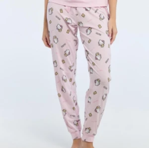 Rosa pyjamasbyxor med Hello Kitty-mönster - Mysiga rosa pyjamasbyxor med ett gulligt Hello Kitty-mönster. Perfekta för en avslappnad kväll hemma. Byxorna har en bekväm passform och är tillverkade i mjukt material. Lite noppriga