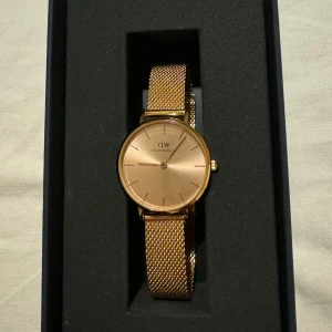 Rosefärgad klocka från Daniel Wellington - Elegant rosefärgad klocka från Daniel Wellington med en stilren urtavla och matchande mesh-armband. Endast testat runt armen 1 gång. Nypris 1900kr