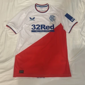 Rangers FC borta-tröja 22/23 - Rangers bortaställ från säsongen 2022/23. Tröjan är helt ny och har lapparna kvar. Den är köpt på sportsdirect.com, och är helt äkta.