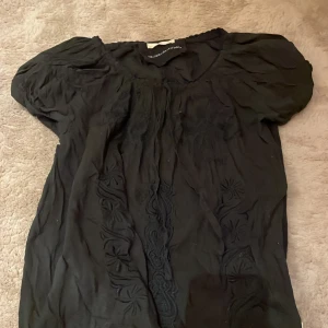Svart blus från Odd Molly - Säljer en svart blus från Odd Molly med broderade detaljer. Blusen har korta ärmar och en rund hals. 