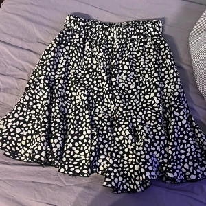 Svart och vit mönstrad kjol från Shein - Snygg svart och vit mönstrad kjol från Shein med elastisk midja. Kjolen har ett lekfullt mönster och volanger som ger en fin rörelse. Perfekt för att liva upp garderoben! Aldrig använd 