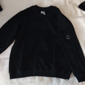 Svart sweatshirt från C.P. Company - Cp company. Allt har qr allt är äkta och stilrena. Tröjorna är i storlek M Tröjan med ärmficka 1000 kr     Tröjan med gogels 1400 kr och Mössan för 450 kr                       Otroligt billigt! 