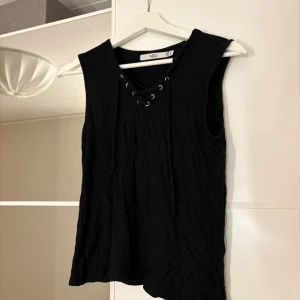 Svart ärmlös topp - Snygg svart ärmlös topp med snörning framtill. Hör av er vid funderingar eller om ni vill ha bilder med hur plagget sitter på mig. Titta gärna in mina andra plagg!