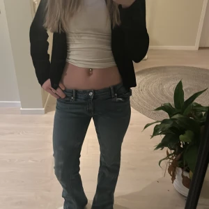Blå jeans från Gina Tricot - Snygga blå jeans från Gina Tricot med klassisk femficksdesign och knappgylf. De har en bootcut-stil som ger en retro känsla. Perfekta för en avslappnad look.