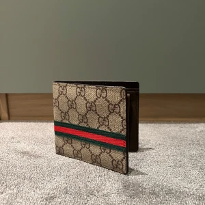 Gucci plånbok  - Nu säljer jag min snygga Gucci plånbok med klassiskt mönster och ikoniska ränder i grönt och rött. Plånboken är helt ny och köpt från min leverantör. Boxen ingår ej. Äkta. Kan va kOp1@ osäker. Hör av dig innan köp och för mer info. 👋😊