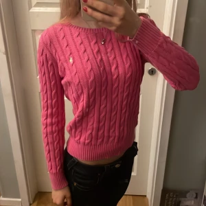Rosa stickad tröja från Ralph Lauren - Säljer en snygg rosa stickad tröja från Ralph Lauren med kabelstickat mönster. Tröjan har långa ärmar och en rund halsringning. 💖 i ny skick. Egentligen i barnstrorlek L men passar som en dam XS/S. 