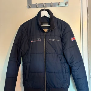 Marinblå jacka Sail Racing - Säljer en mörkblå Sail Racing jacka. Perfekt nu på våren men även höst då den håller dig varm i vinden. Nypris ca 2499. Storlek S