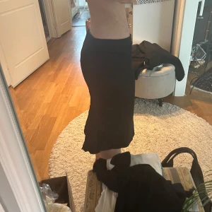 Svart kjol - Snygg svart kjol med en  unik design. Kjolen är lågmidjad. Den ger en enkel topp en extra touch, vilket gör den lätt att matcha med olika toppar.