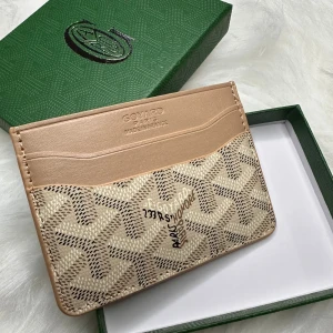 Beige och brun plånbok  - Snygg och stilren plånbok  i beige och brun med klassiskt mönster. Plånboken har flera kortfack och en insida i en överraskande gul färg. Perfekt för att hålla ordning på dina kort med stil.