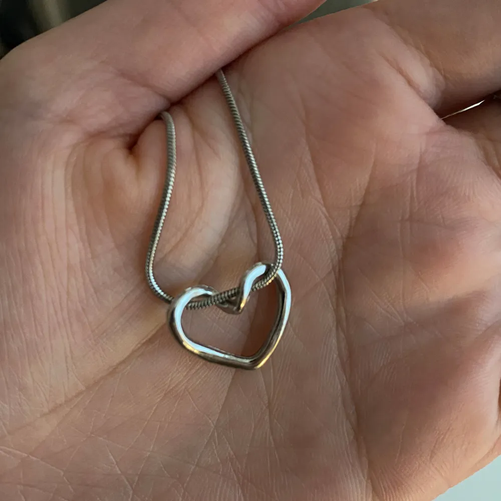 Elegant silverfärgat halsband med ett stilrent hjärta som hänge. Perfekt för att ge en subtil touch av kärlek till din outfit. Kedjan är tunn och smidig, vilket gör den bekväm att bära hela dagen.. Asusteet.